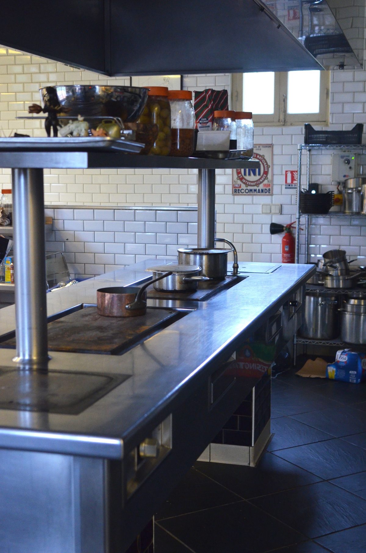 Commercial restaurant kitchen with stainless steel pass, extraction hood and cookware
