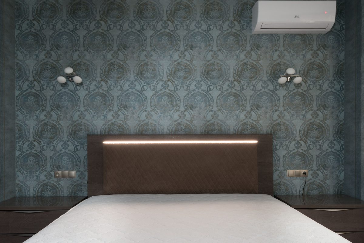 Patterned wallpaper feature wall behind a bed headboard in a bedroom
